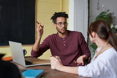 A man explains business continuity to a woman, and a laptop is kept on the table.